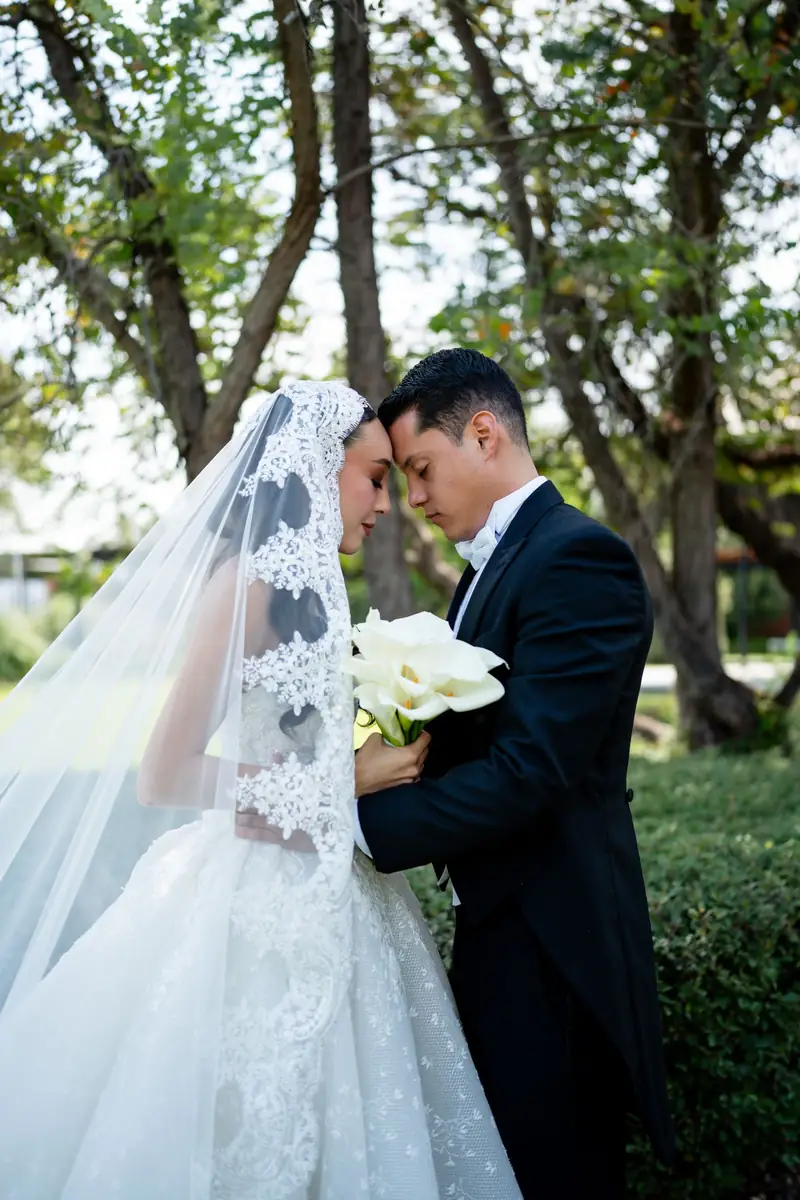 Couple forehead to forehead, bride in a lace mantilla, in the garden at La Folié Eventos