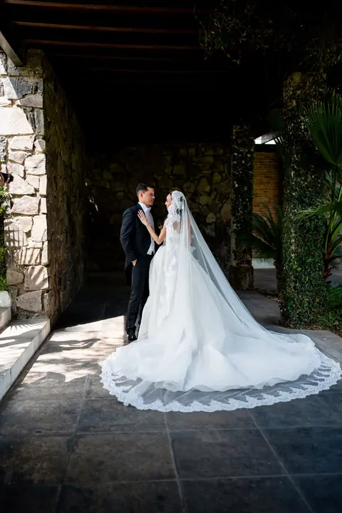 Novia con velo largo en un corredor de piedra