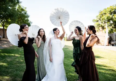 Novia y damas con sombrillas blancas en el jardín
