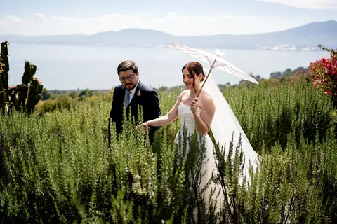 Novios con sombrilla en un jardín frente al Lago de Chapala
